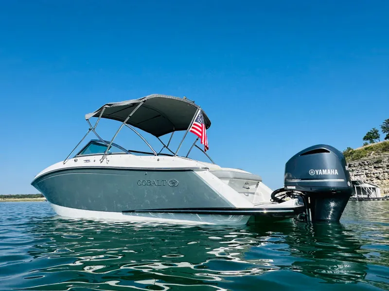 Slide: The Image of 2018 Cobalt 23SC boat with Yamaha engine on clear water, American flag displayed. - 2