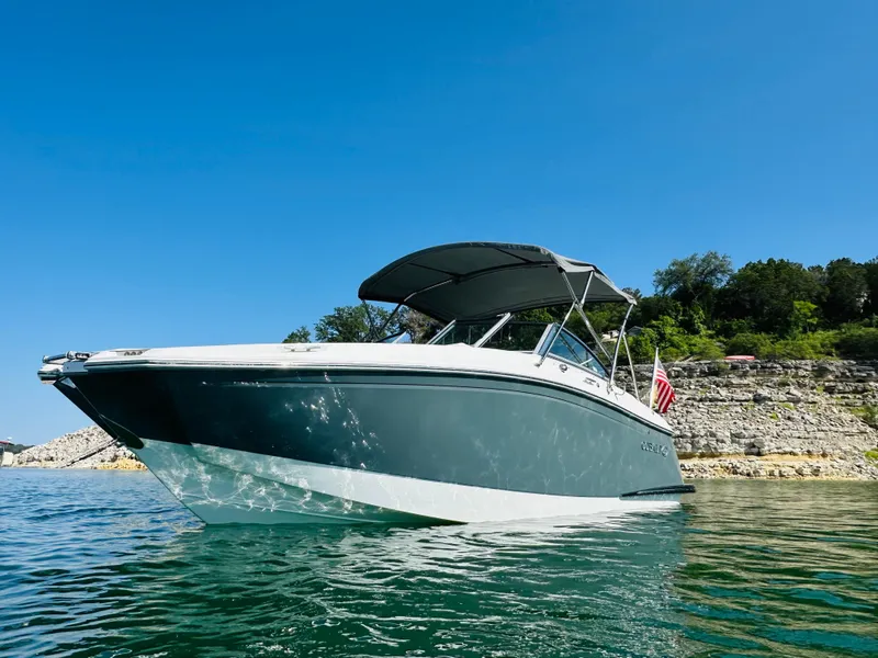Slide: The Image of 2018 Cobalt 23SC boat on clear water with rocky shoreline and blue sky. - 3