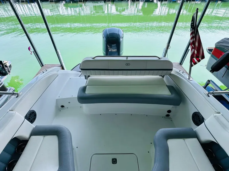 Slide: The Image of 2018 Cobalt 23SC boat interior with seating, outboard motor, and American flag on a calm lake. - 32