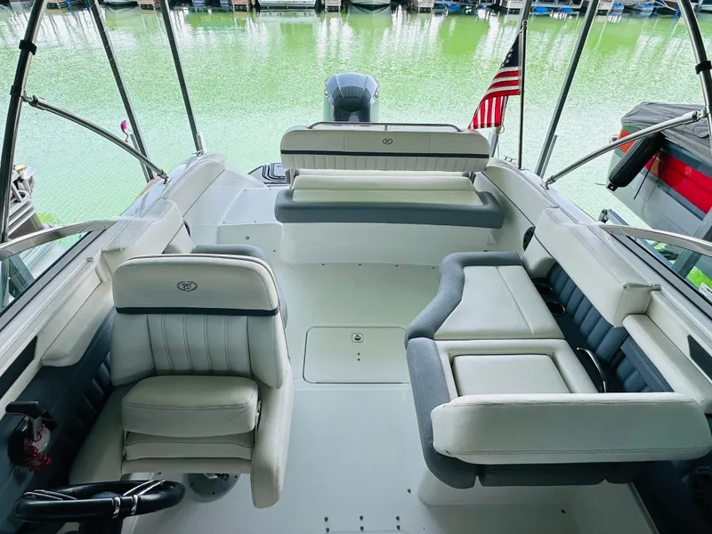 Slide: The Image of 2018 Cobalt 23SC boat interior with seating, docked by green water. - 39