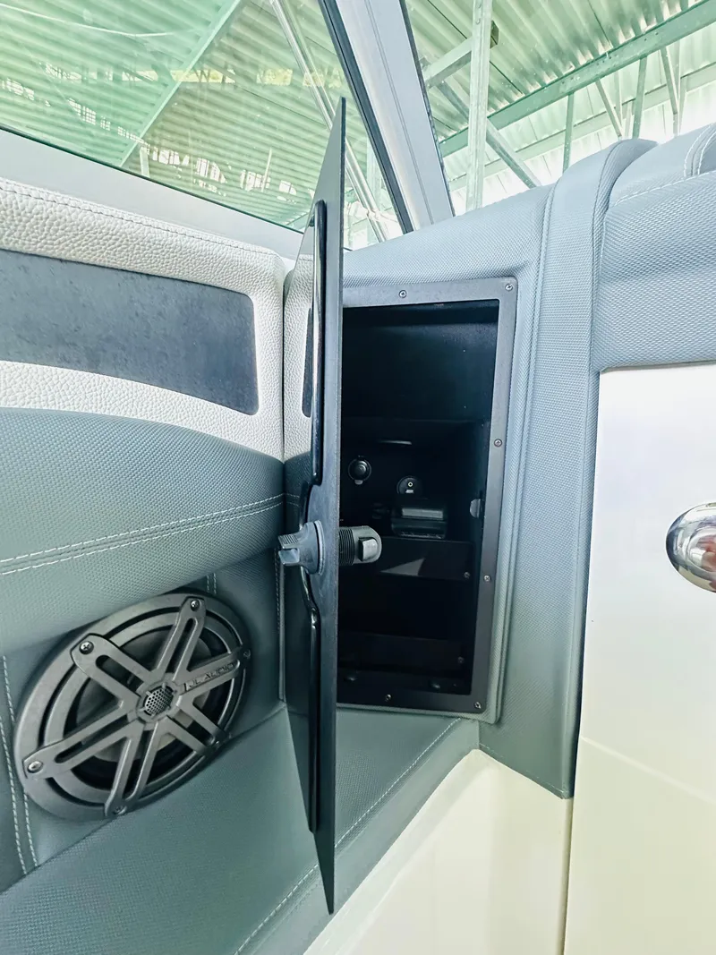 Slide: The Image of 2018 Cobalt 23SC boat interior with open storage compartment and speaker. - 44