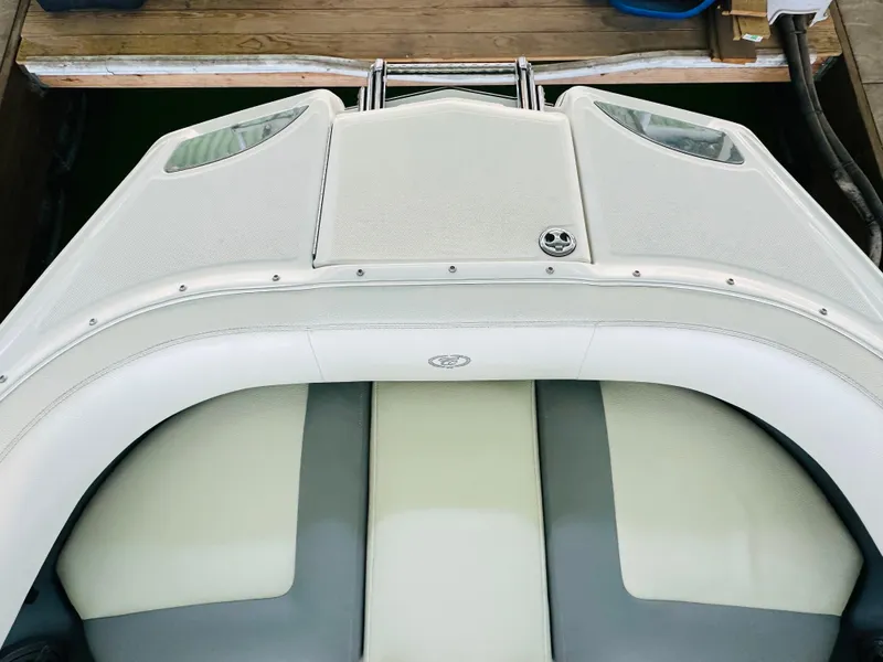 Slide: The Image of 2018 Cobalt 23SC boat interior with white and gray seating, docked at a wooden pier. - 49