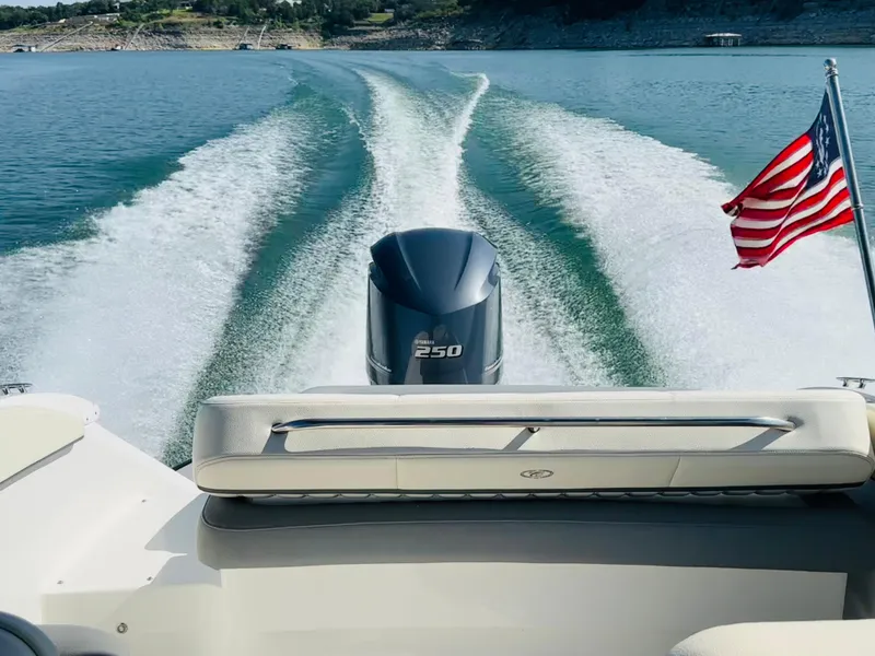Slide: The Image of 2018 Cobalt 23SC boat cruising on a lake with American flag and wake trail. - 9