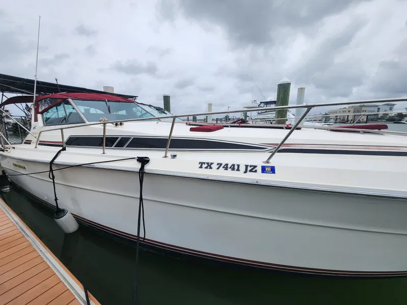 Slide: The Image of 1987 Sea Ray 390 Express Cruiser docked, featuring sleek design and red canopy. - 1