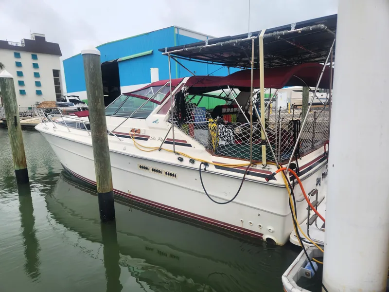 Slide: The Image of 1987 Sea Ray 390 Express Cruiser docked at marina, featuring maroon canopy and white hull. - 3
