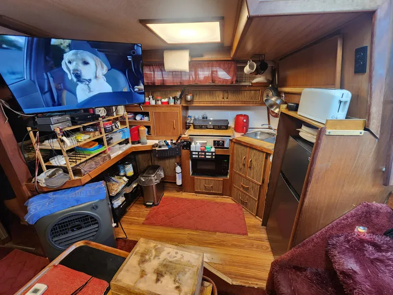 Slide: The Image of 1987 Sea Ray 390 Express Cruiser interior with kitchen, TV, and wooden cabinetry. - 5