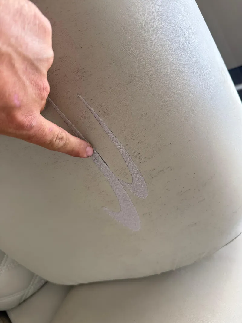 Slide: The Image of Torn upholstery on 2014 Bennington 2550 RCB boat seat with finger pointing at damage. - 27