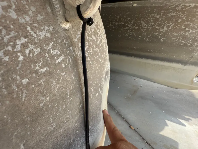 Slide: The Image of Close-up of 2014 Bennington 2550 RCB boat hull with visible wear and a pointing finger. - 8