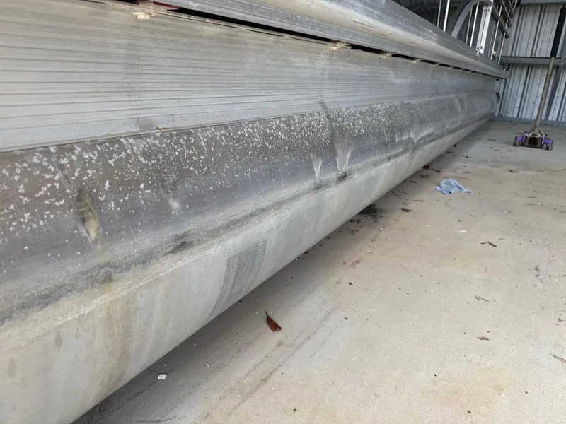 Slide: The Image of 2014 Bennington 2550 RCB pontoon boat with visible wear and dirt on the hull. - 9