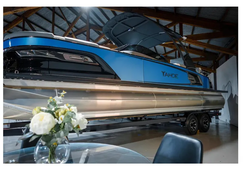 Slide: The Image of 2025 Tahoe Grand Tahoe LTD pontoon boat in showroom with floral centerpiece. - 1