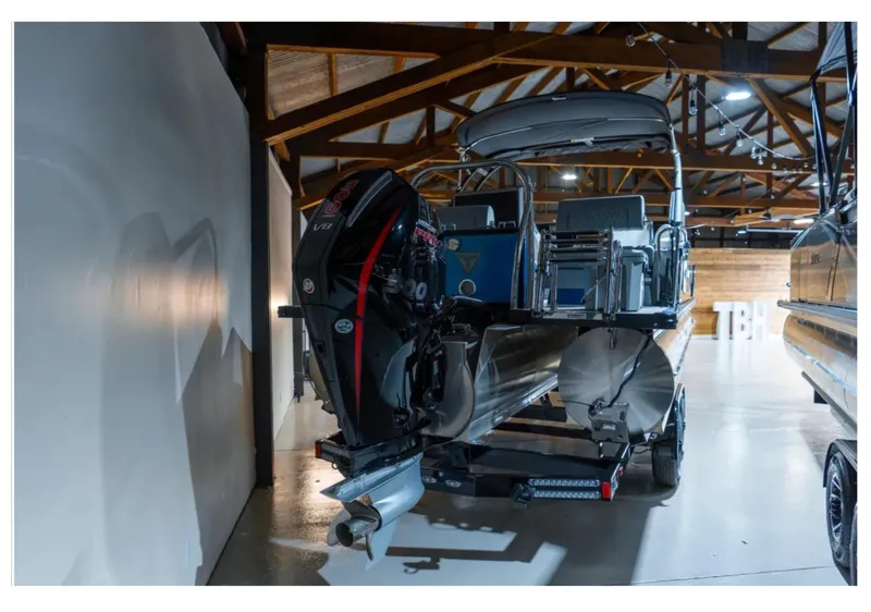 Slide: The Image of 2025 Tahoe Grand Tahoe LTD pontoon boat with powerful outboard motor in showroom. - 2