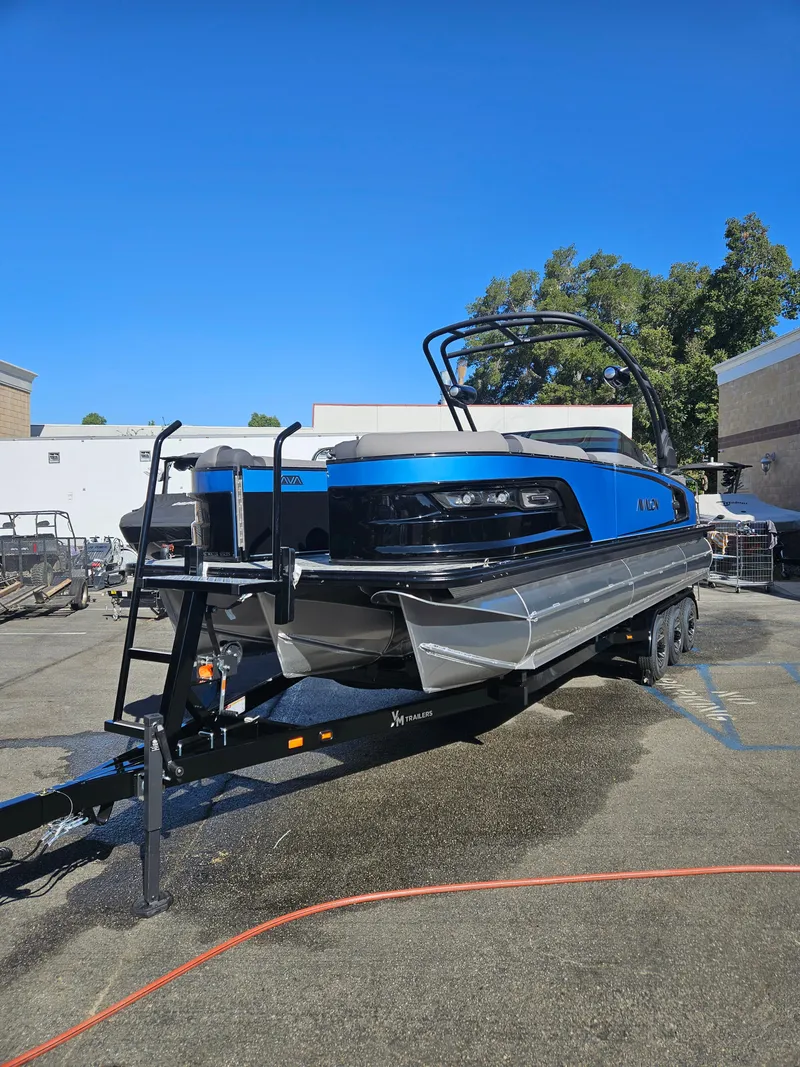 Slide: The Image of 2025 Avalon Excalibur LTD Elite Windshield 27FT boat on trailer, parked outdoors. - 11