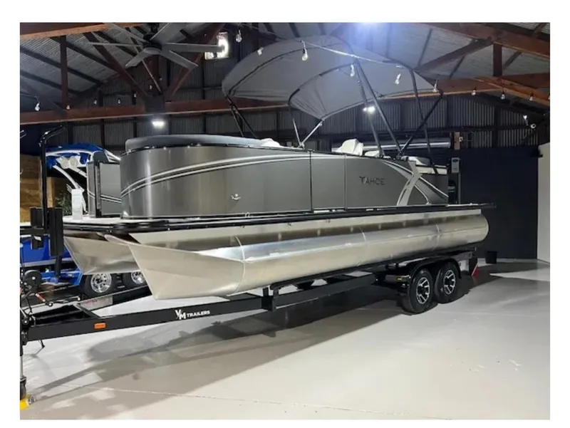 Slide: The Image of 2025 Tahoe LTZ pontoon boat on trailer in indoor showroom. - 1