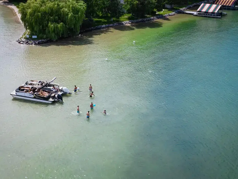 Slide: The Image of Aerial view of people swimming near a boat in a scenic lake. - 19
