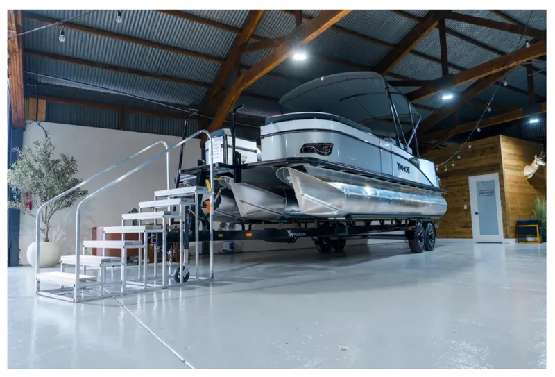 Slide: The Image of 2025 Tahoe CASCADE pontoon boat displayed indoors on a trailer with stairs. - 8