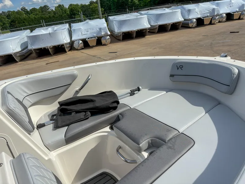 Slide: The Image of 2021 Bayliner VR4 boat interior with cushioned seating and storage, docked outdoors. - 5
