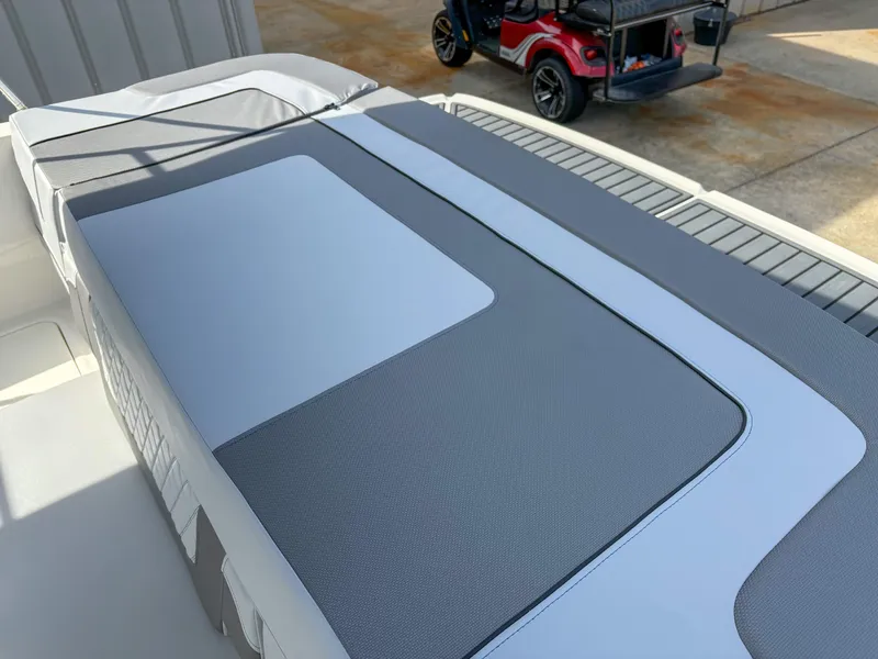 Slide: The Image of 2021 Bayliner VR4 boat interior with gray and white seating, parked near a red golf cart. - 8
