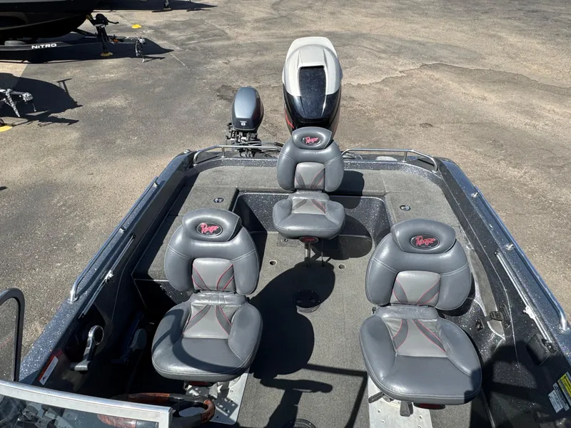 Slide: The Image of 2004 Ranger 619 VS Fisherman boat with four gray seats and motor, parked on pavement. - 10