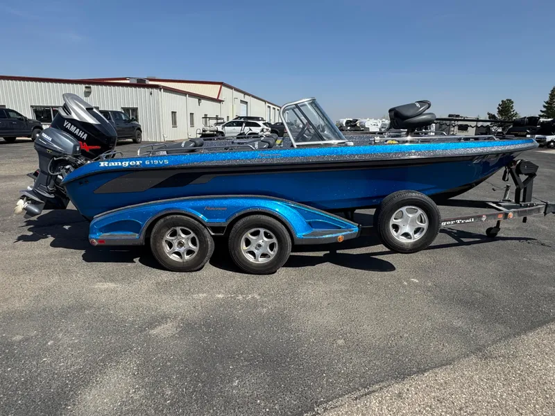 Slide: The Image of 2004 Ranger 619 VS Fisherman boat, blue, on a trailer in a parking lot. - 3