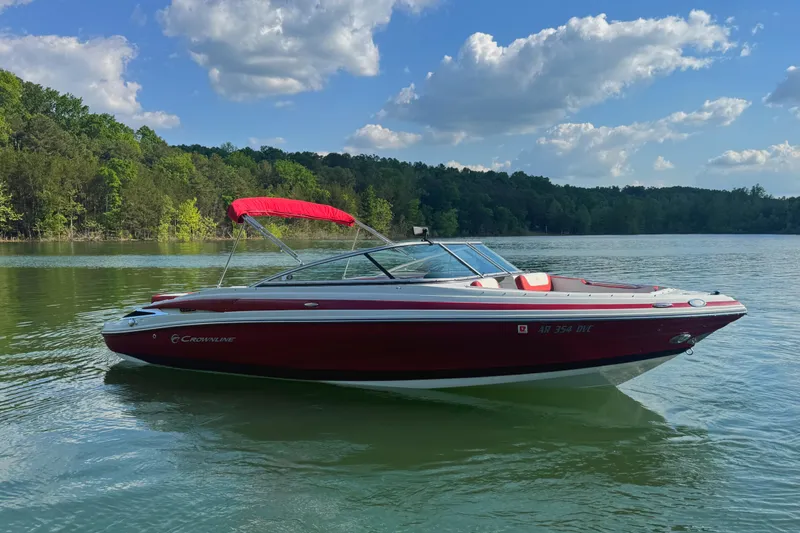 The Image of 2018 Crownline 225SS boat with red canopy on a serene lake. - 0
