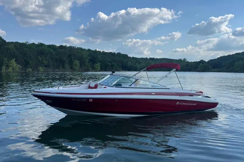 Slide: The Image of 2018 Crownline 225SS boat on a serene lake with lush forest background. - 1