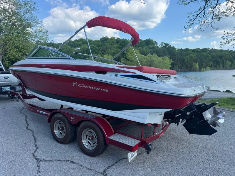 Slide: The Image of 2018 Crownline 225SS boat on trailer by a lake, red and white design. - 16