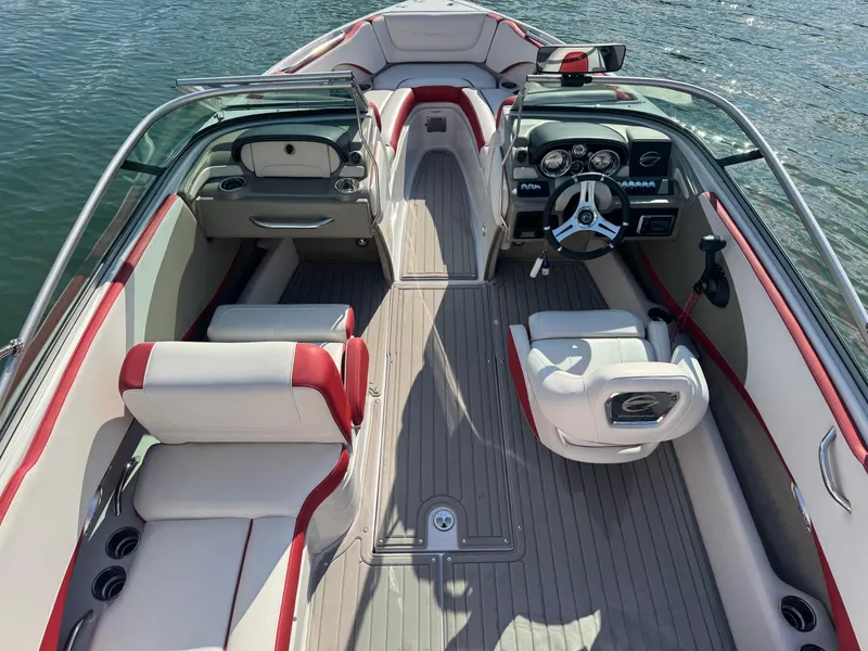 Slide: The Image of 2018 Crownline 225SS boat interior with red and white seating, steering wheel, and dashboard. - 2