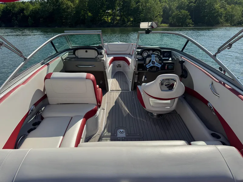 Slide: The Image of 2018 Crownline 225SS boat interior with red and white seating on a sunny lake. - 3