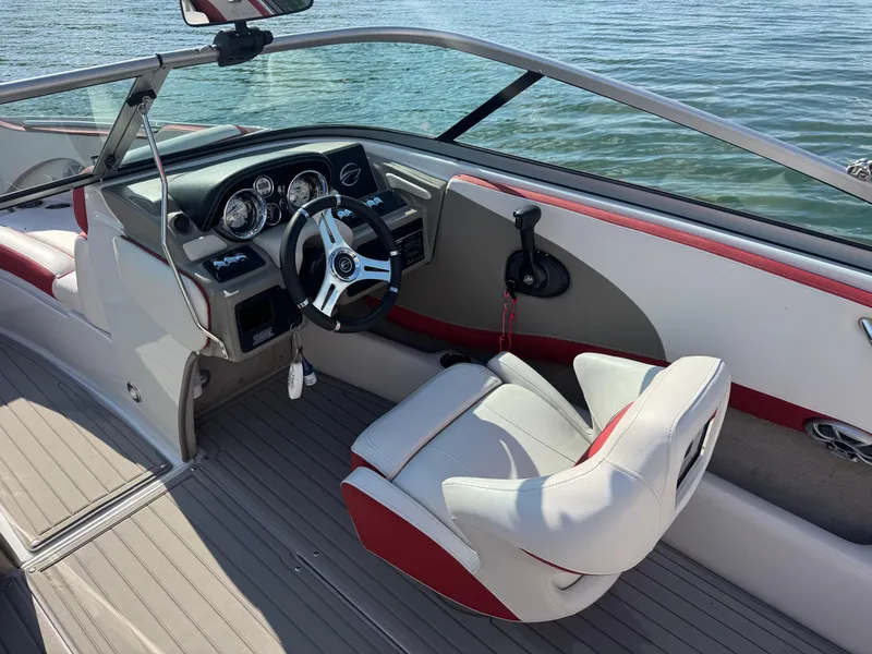 Slide: The Image of 2018 Crownline 225SS boat interior with steering wheel and seating, on calm water. - 8