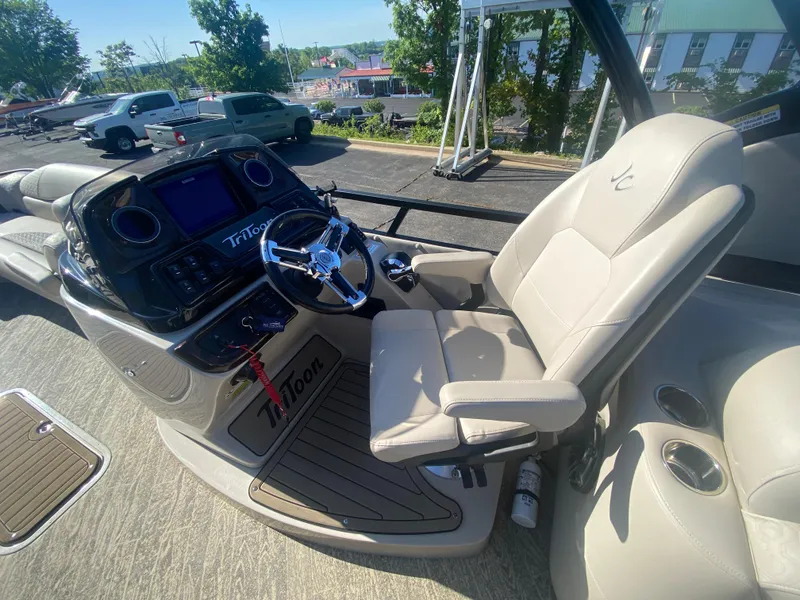 Slide: The Image of 2023 JC Sporttoon 26TT boat interior with steering console and comfortable seating. - 16