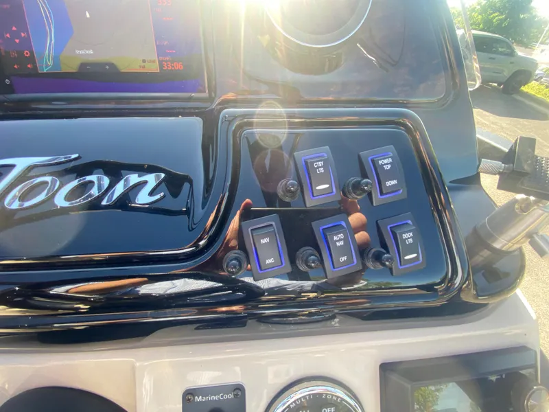 Slide: The Image of Control panel of 2023 JC Sporttoon 26TT boat with switches and sunlight reflection. - 21