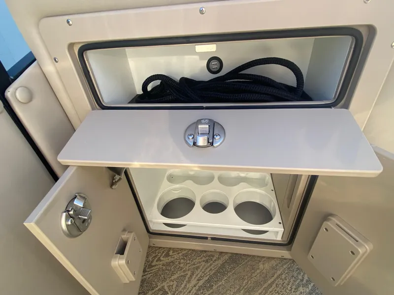 Slide: The Image of 2023 JC Sporttoon 26TT storage compartment with cup holders and coiled rope. - 30