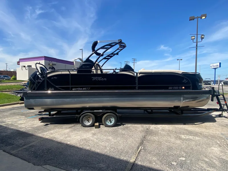 Slide: The Image of 2023 JC Sporttoon 26TT pontoon boat on trailer, parked outdoors under clear blue sky. - 5