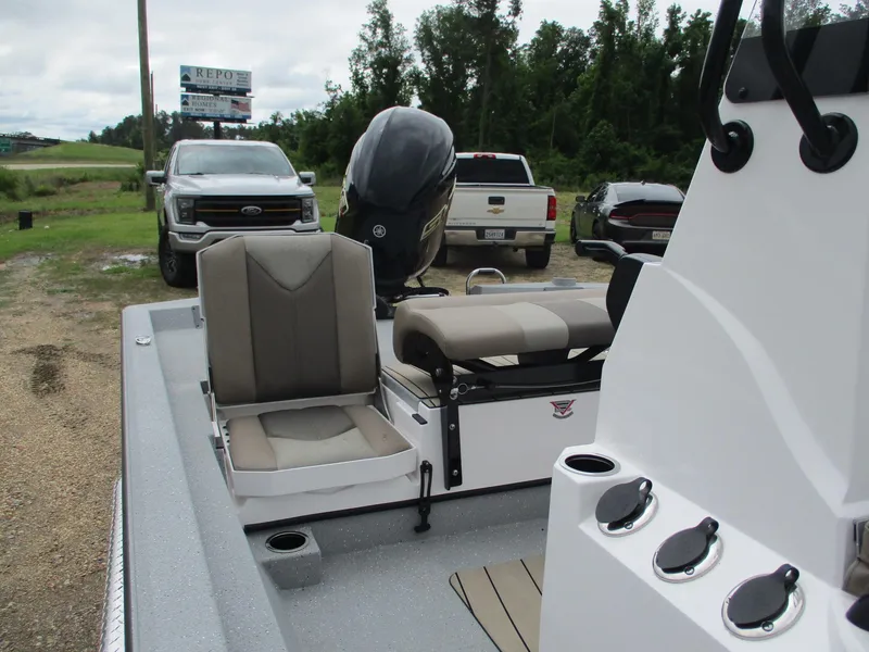 Slide: The Image of 2025 Vexus ACX2000 boat interior with seating and motor, parked near vehicles. - 9