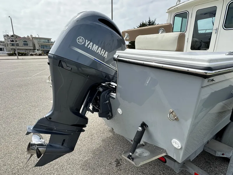 Slide: The Image of 2019 Parker 2120 Sport Cabin boat with Yamaha outboard motor in a parking lot. - 2