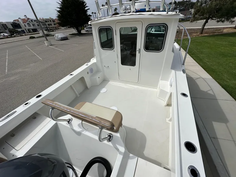 Slide: The Image of 2019 Parker 2120 Sport Cabin boat with spacious deck and seating, parked outdoors. - 4