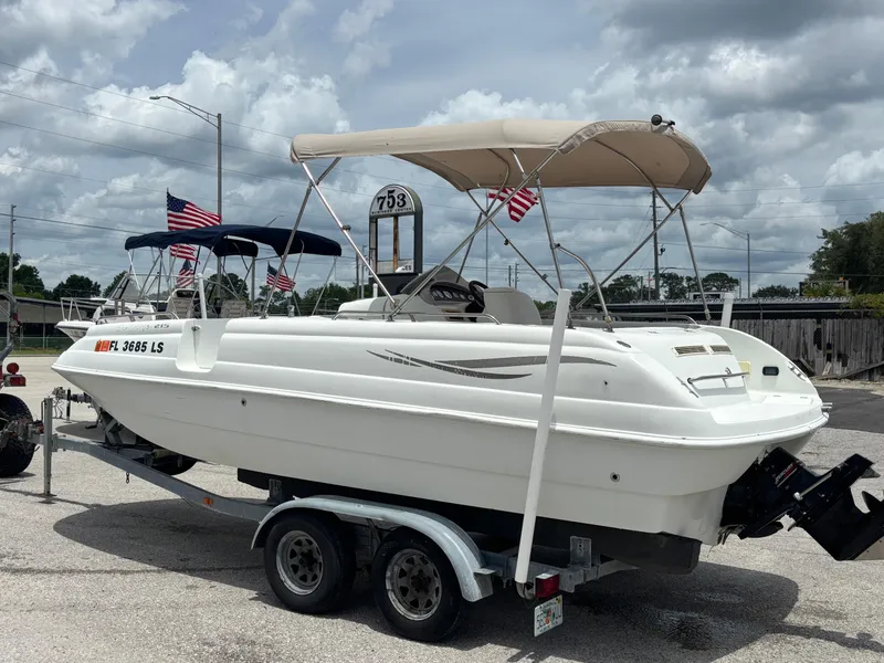 Slide: The Image of 2002 Monark Sunlounger 215 boat on trailer with canopy and American flags. - 1