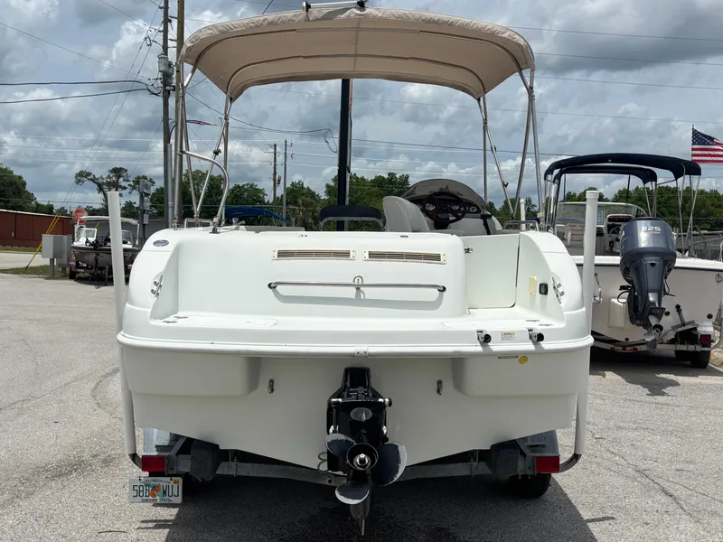 Slide: The Image of 2002 Monark Sunlounger 215 boat with canopy, parked in a lot under cloudy skies. - 3