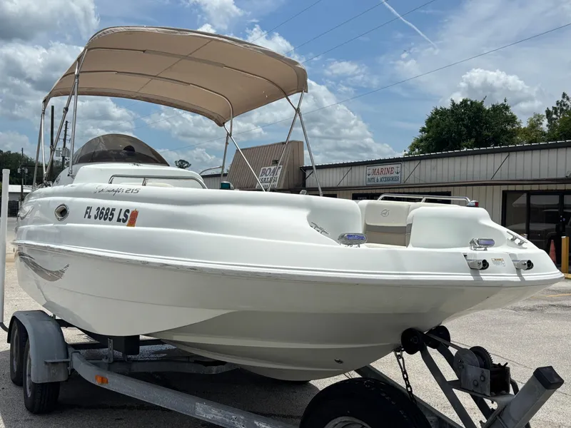 Slide: The Image of 2002 Monark Sunlounger 215 boat on trailer, parked outdoors under a cloudy sky. - 6