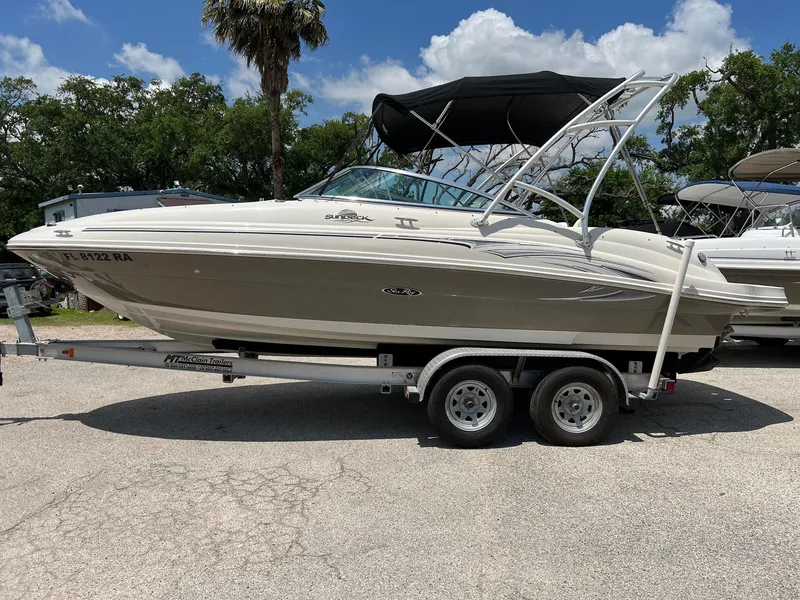 Slide: The Image of 2005 Sea Ray 220 Sundeck boat on trailer, parked outdoors under a sunny sky. - 27