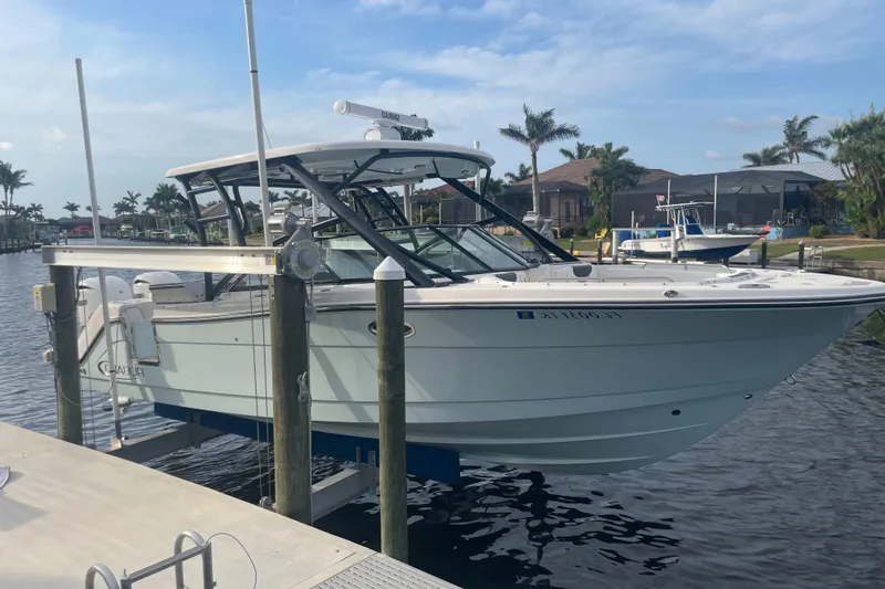 The Image of 2023 Robalo R317 Dual Console boat docked in a marina with palm trees. - 0