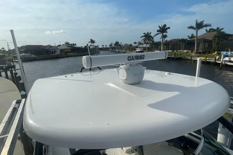 Slide: The Image of 2023 Robalo R317 Dual Console boat docked by a scenic waterfront. - 2