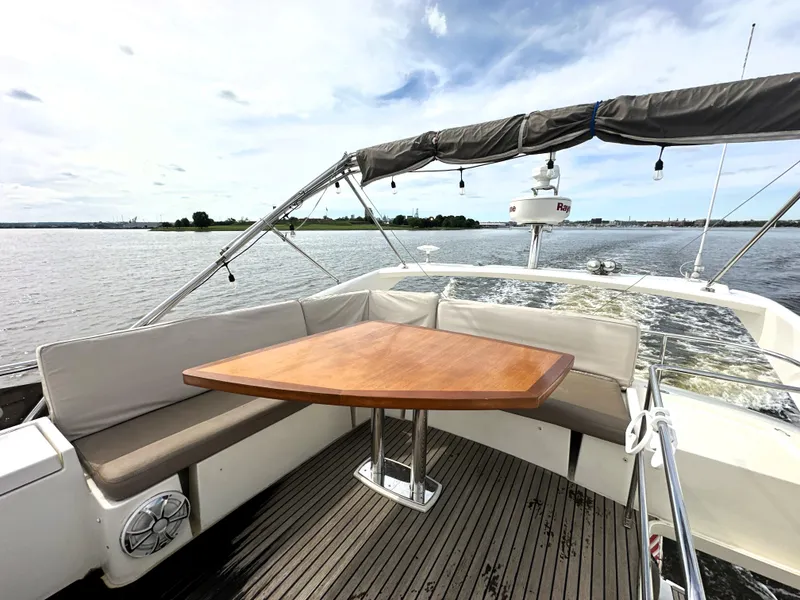 Slide: The Image of Prestige 500 yacht deck with wooden table, cushioned seating, and scenic water view, 2013 model. - 10