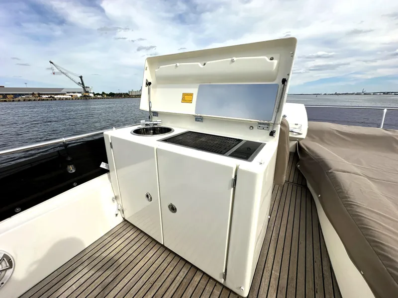 Slide: The Image of Outdoor kitchenette on 2013 Prestige 500 yacht with sink and grill, docked by the water. - 11