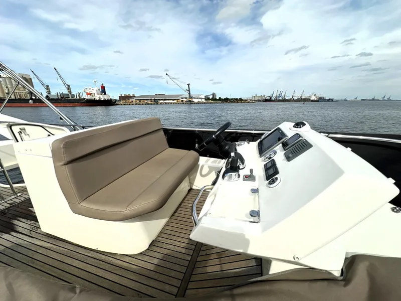 Slide: The Image of 2013 Prestige 500 yacht helm with brown seating, overlooking a harbor. - 12