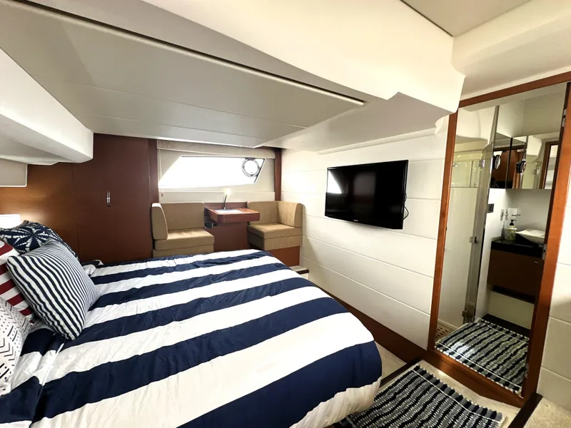 Slide: The Image of Luxurious 2013 Prestige 500 yacht bedroom with striped bedding, seating area, TV, and ensuite bathroom. - 42