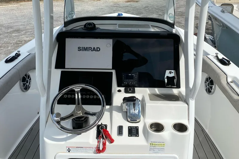 Slide: The Image of 2021 Sea Pro 239 Center Console boat dashboard with Simrad display and steering wheel. - 5