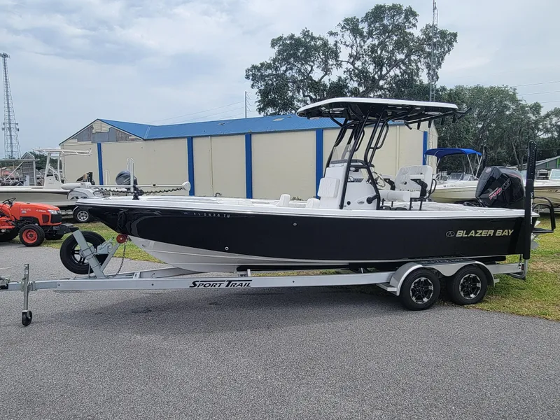 Slide: The Image of 2024 Blazer Bay 2440 boat on trailer, parked outdoors near blue-roofed building. - 5