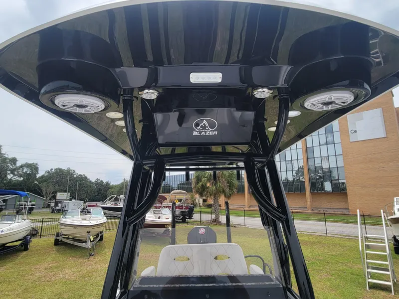 Slide: The Image of 2024 Blazer Bay 2440 boat with T-top and speakers, displayed outdoors. - 7