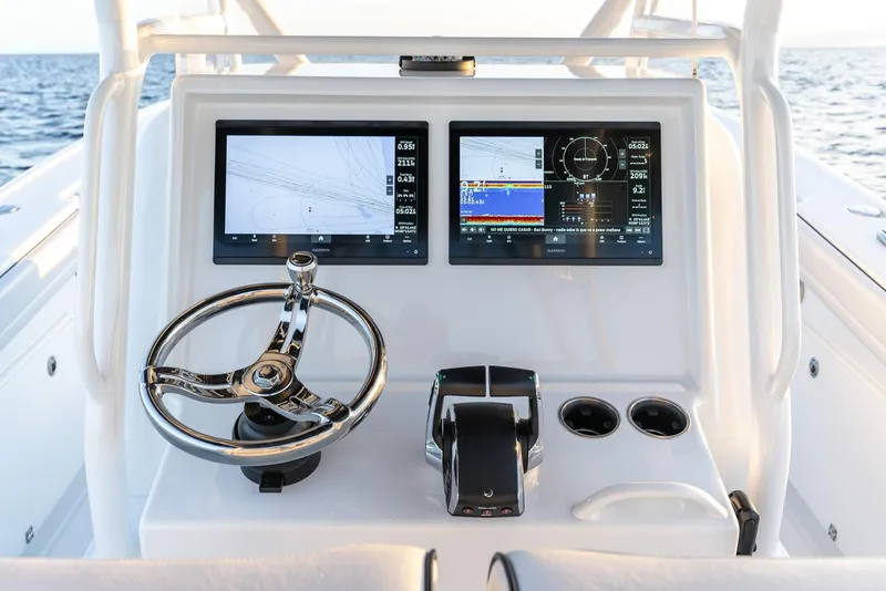 Slide: The Image of 2023 Yellowfin 34 boat dashboard with dual screens and steering wheel, ocean in background. - 12